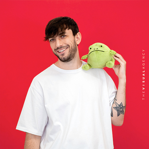 Mattia Casarotto is the Multimedia Designer. He is holding a green frog puppet, just like his work: adaptable and always ready to leap between media.