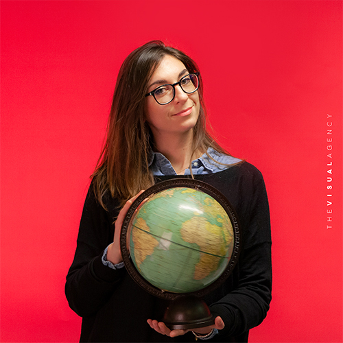 Veronica Clarin is the Senior Information Designer. She's clutching a globe as if she’s about to remap the Earth itself.