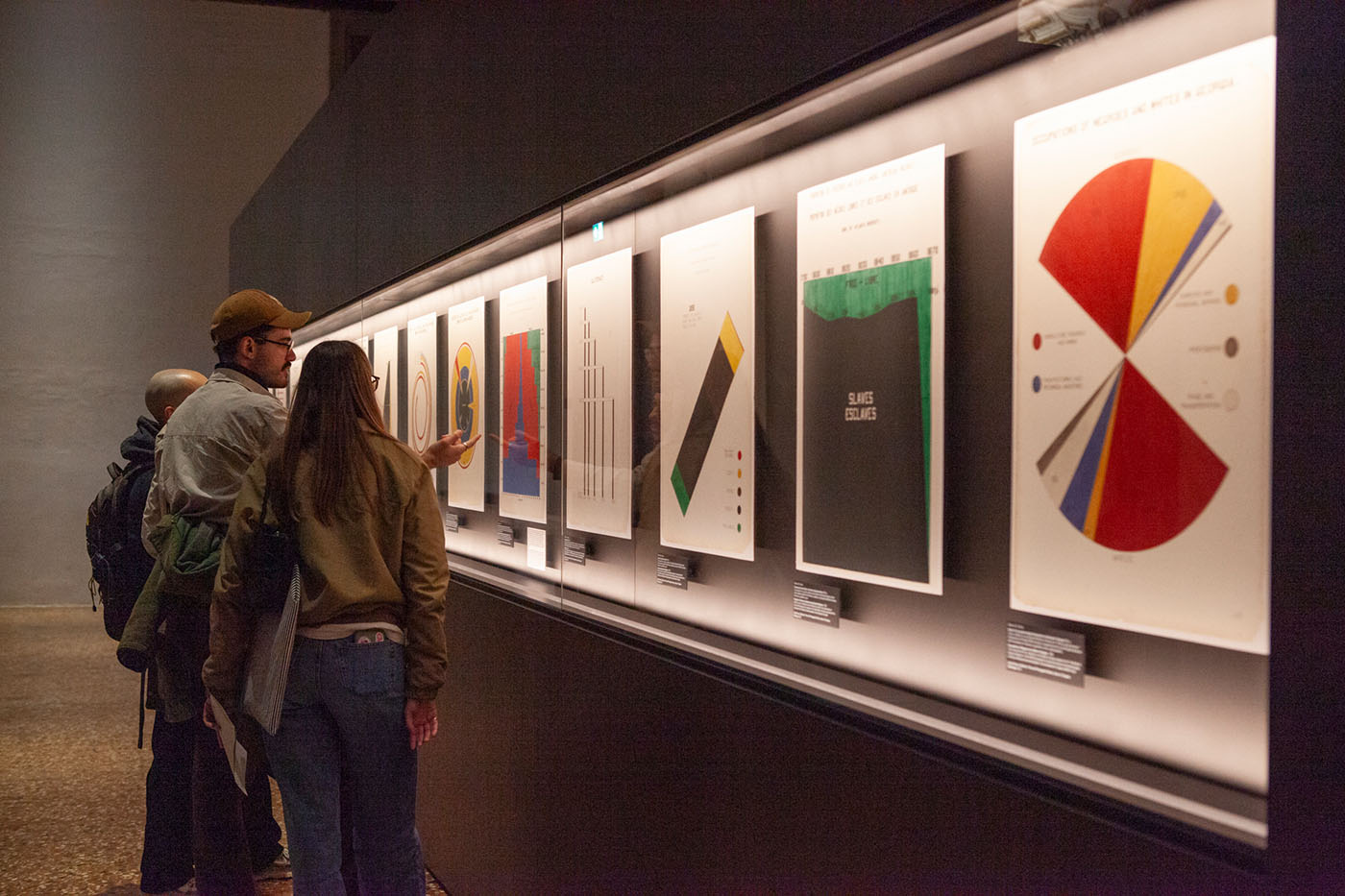 Three members of The Visual Agency view data-visualization posters at OMA’s “DIAGRAMS” exhibition.